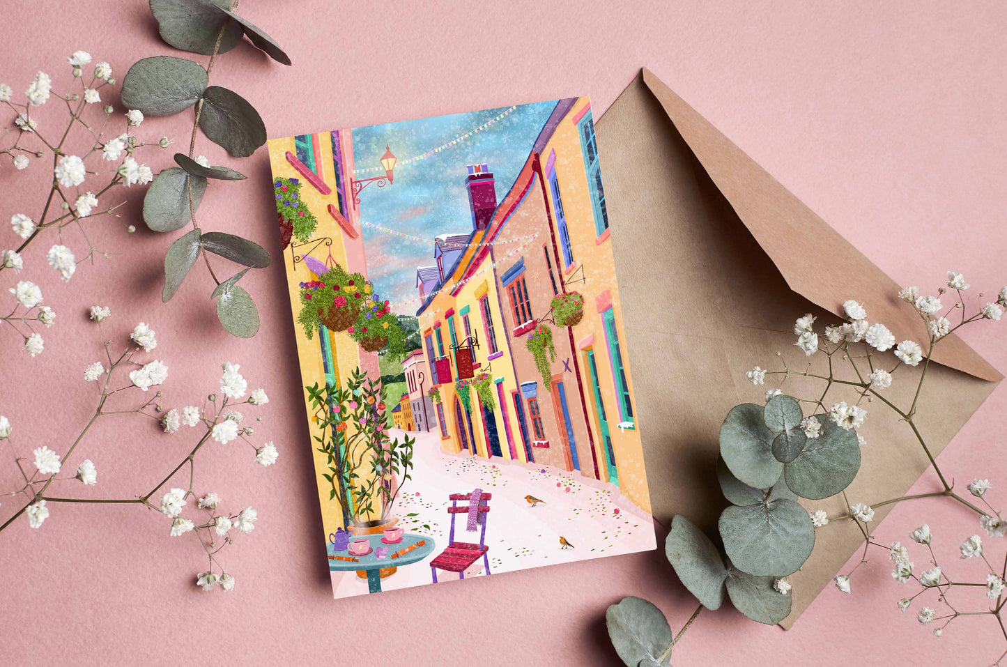 Colorful greeting card with a street scene, envelope, and decorative elements on a pink background