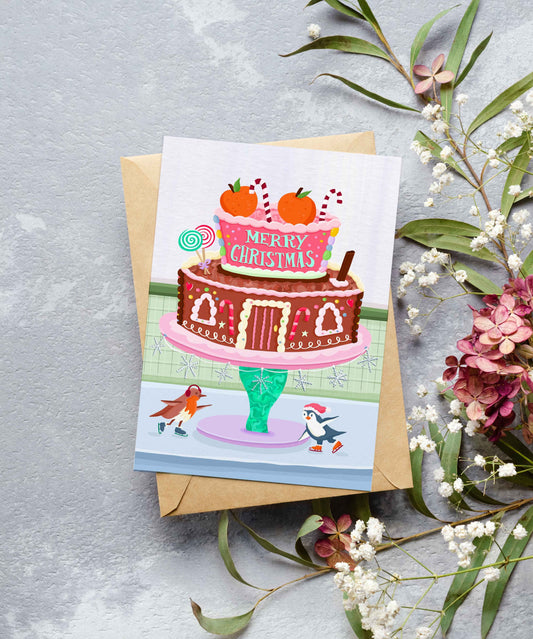 Christmas card with a cake illustration on a gray surface with floral decorations